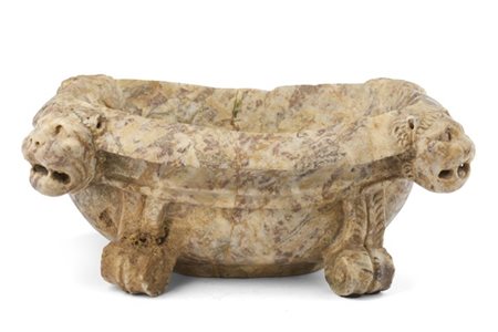 Antica vasca in marmo scolpito di forma ovale con anse a volti leonini, piedi a