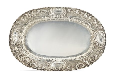 Vassoio in argento sbalzato con falda decorata a volute fogliate e graticci inc
