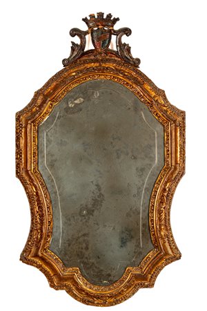 Specchiera di forma mossa con cornice in legno intagliato e dorato, cimasa a stemma. Secolo XIX