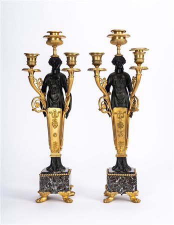 Coppia di candelabri in bronzo dorato e patinato su basi in marmo. Secolo XIX
