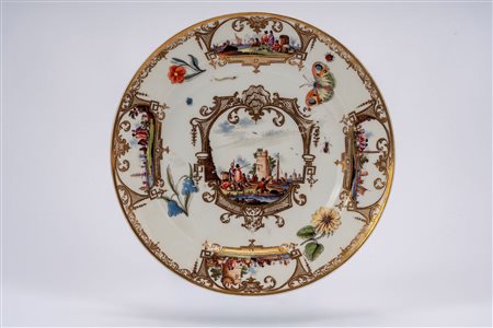 MPiatto in porcellana bianca decorata con dorature e in policromia a scene portuali entro riserve tra fiori, farfalla e insetti sparsi. Meissen, 1740 circa.