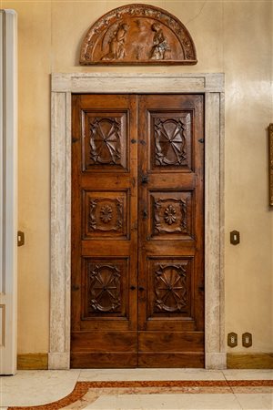Porta a due battenti in noce massello con pannelli intagliati a motivi geometrici e palmette entro riserve sagomate. Piemonte, secolo XVII.