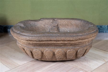 Vasca in pietra. Secolo XVII-XVIII. Corpo ovale con bordo modanato e fascia inferiore ornata da baccellature.