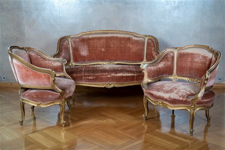 Fornitura da salotto composta da un divano e due poltrone di forma mossa e avvolgente in legno dorato. Secolo XIX.