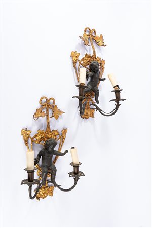 Coppia di appliques a due luci in bronzo dorato e patinato con sostegno decorato da putto a rilievo. Secolo XIX.