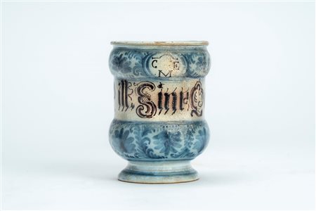 Albarello in maiolica con decoro blu cobalto  a motivi vegetali interrotto da cartiglio con scritta apotecaria a caratteri gotici "Sine Quib", secolo XVIII