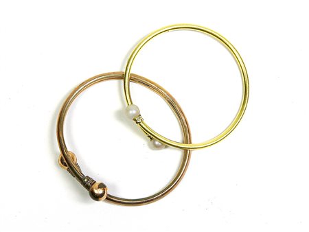 Due bracciali rigidi a cerchio uno in oro a basso titolo con finali con perle...