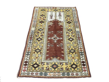 Tappeto turco fondo marrone e giallo, campo con motivi geometrici nei toni...