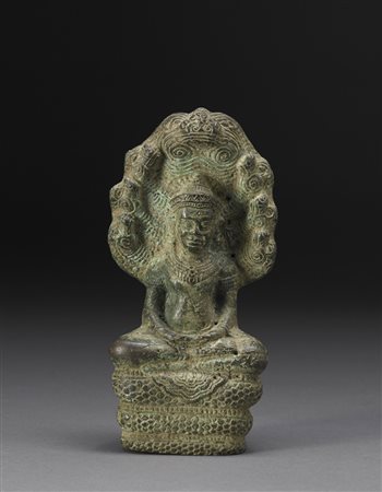 Divinità in bronzo seduta a gambe incrociate su un serpente a spirale, le...