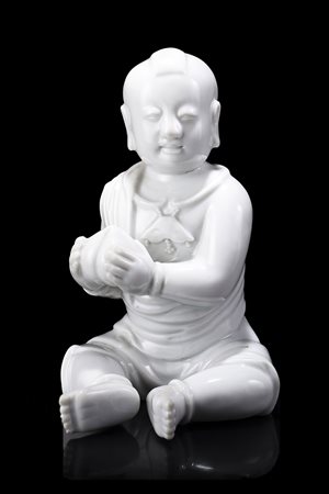 Fanciullo in Blanc-de-Chine raffigurato seduto con una pesca in mano; con...