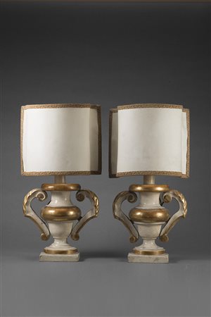 Coppia di portapalme biansate in legno dorato laccato e intagliato a volute...