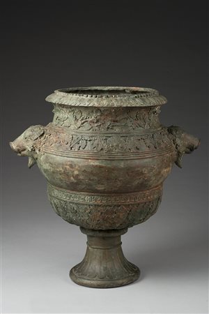 Vaso portafiori in ferro decorato a motivi fogliati. Anse a teste zoomorfe...