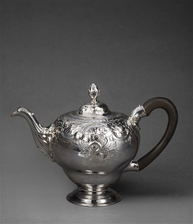 Teiera in argento a corpo globulare sbalzata a volute e fiori. Piede...