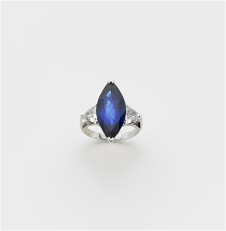 Anello in oro bianco con due diamanti triangolari ai lati di uno zaffiro a...