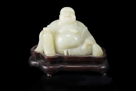 Buddha in giada color celadon chiaro, raffigurato seduto, la tunica aperta...