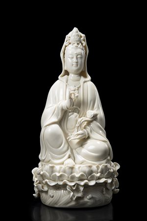 Guanyin in porcellana Blanc-de-Chine, raffigurata seduta su base con fiori di...