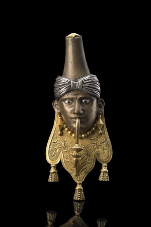 Fregio in bronzo dorato e argentato a figura d'arabo con occhi in smalto....