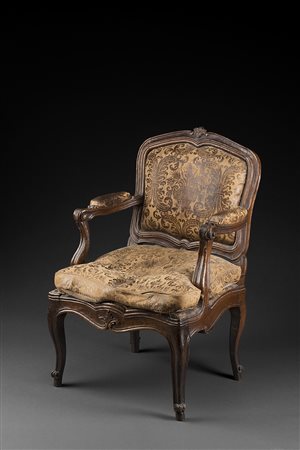 Poltrona in noce con schienale sagomato e cimasa intagliata. Braccioli e...