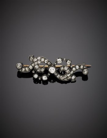 Spilla in oro giallo e argento a volute con diamanti, il centrale taglio a...