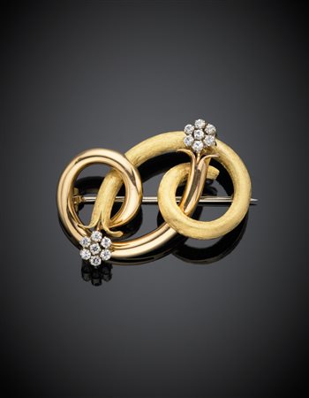 Spilla a volute in oro giallo in parte satinato e pietre incolori a formare...