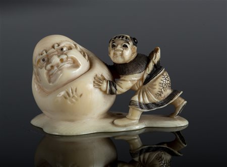 Arte Giapponese Netsuke in avorio raffigurante un bambino che spinge Daruma....
